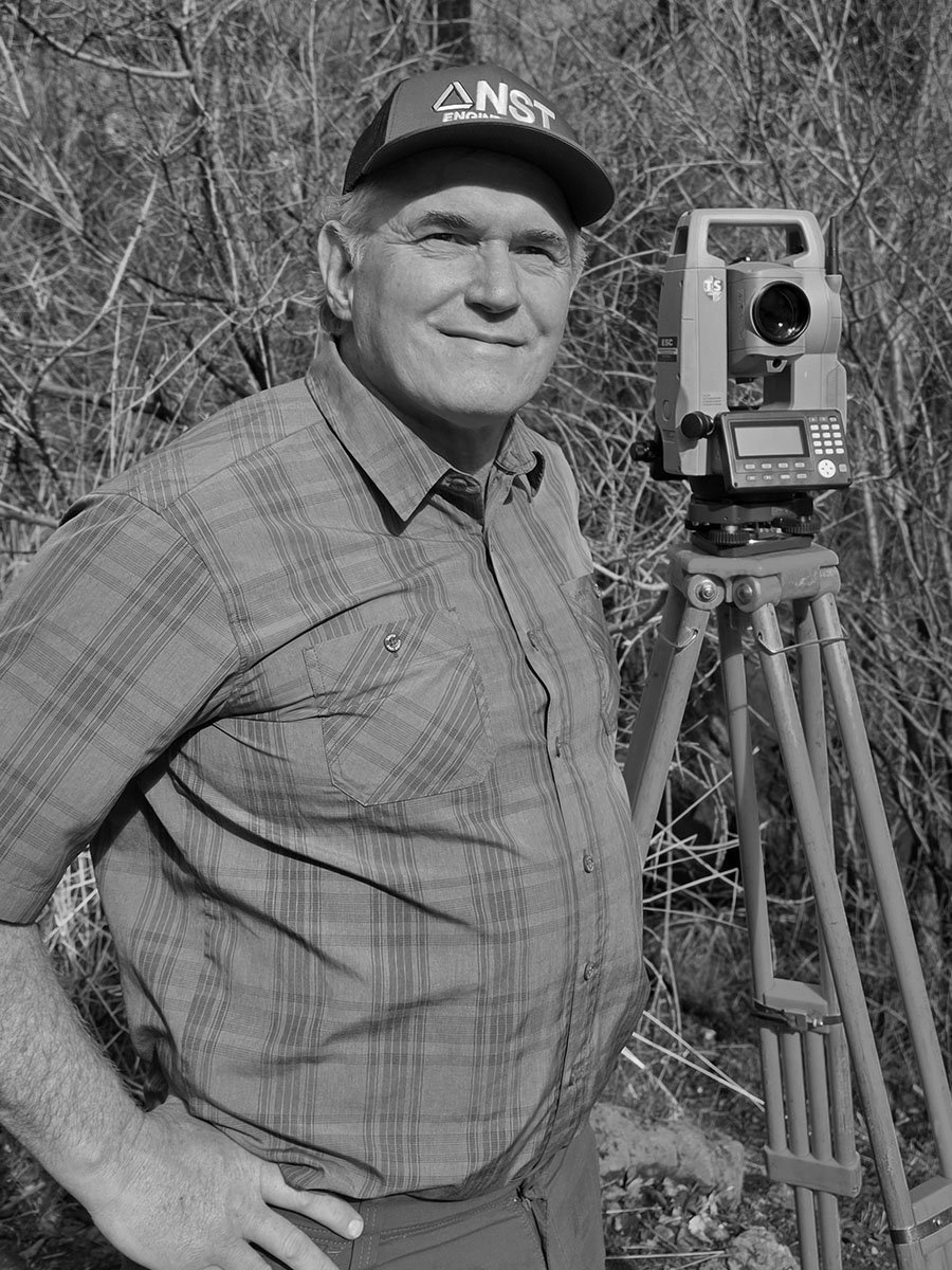 Man in plaid shirt and cap with surveying equipment outdoors